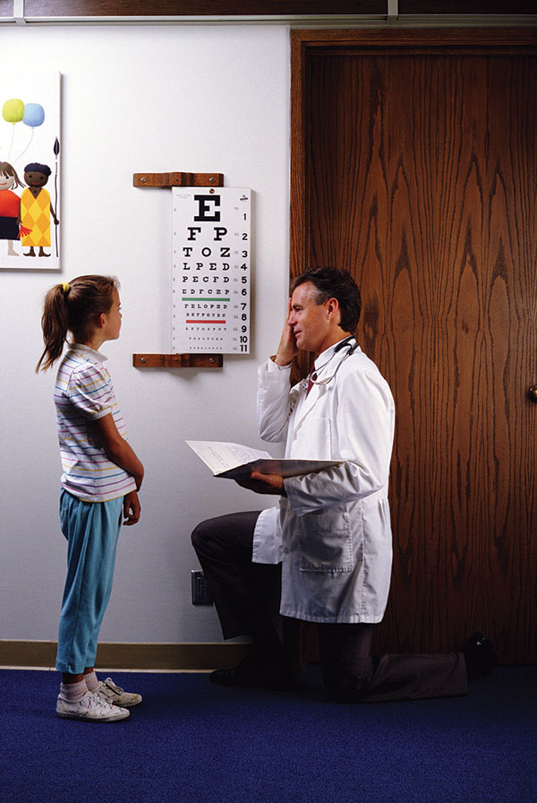 Optometrist with girl by eye chart